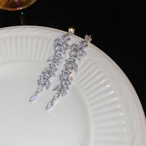 Macro detail of silver leaf tassel earrings with sparkling cubic zirconia on ceramic tray