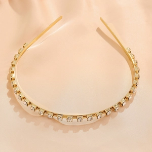 Detail of gold metal headband with sparkling clear rhinestones on beige silk fabric