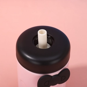 Detail of pink vacuum flask lid featuring a black bow and white straw nozzle