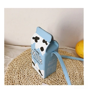 Detail view of milk box cross-body bag with blue cow print and adjustable strap