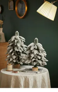 Detail of two flocked mini Christmas trees on wooden bases with Merry Christmas sign