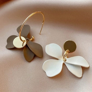 Detail of floral petal earrings in brown and white on a champagne silk background