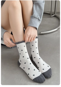 Détail de chaussettes en coton blanc à pois gris avec bordure volantée à l'ourlet