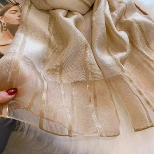 Macro detail of silk wool scarf with golden stripes and light transparent texture