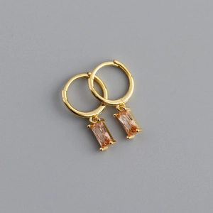 Dettaglio di orecchini a cerchio dorati con eleganti pendenti rettangolari in cristallo champagne