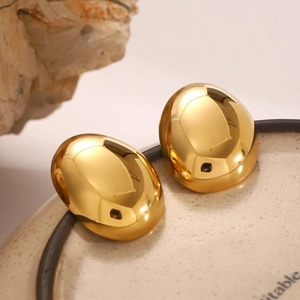 Polished 18k gold plated stainless steel oval hoop earrings on a ceramic dish