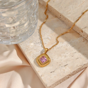 Detail of gold rhombus pendant with pink square zircon and vintage textured metal frame