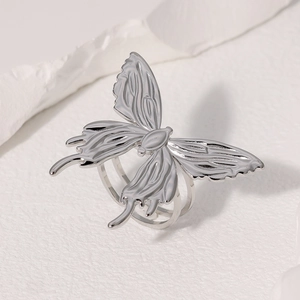 Détail d'une bague papillon argentée au design minimaliste avec finition métallique polie