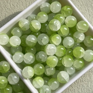 Macro view of 10mm green iced glass beads with cloud patterns in a white container