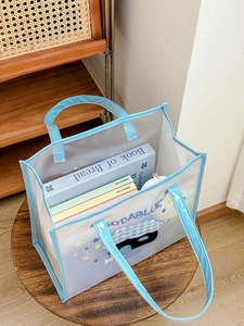 Detail of waterproof PVC tote bag with cute cat print and Soda Blue logo on wood stool