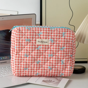 Gros plan sur la trousse à maquillage matelassée à carreaux rouge et blanc avec rubans