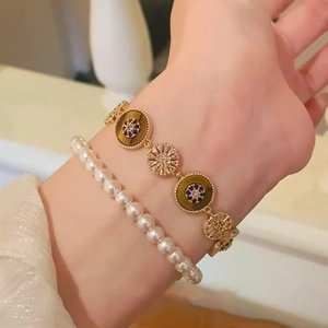 Détail d'un ensemble de bracelets dorés avec perles blanches et disque en œil de tigre