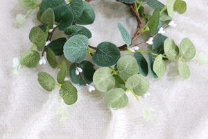 Detailed macro view of artificial eucalyptus leaves and white berries on a plush background