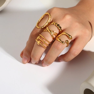Detailed view of five 18K gold plated stainless steel rings layered on model fingers