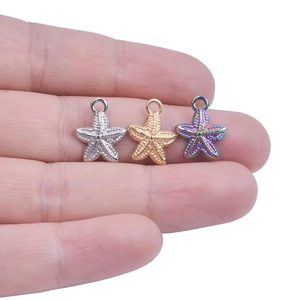 Golden and rainbow starfish charms in stainless steel held between fingers for size