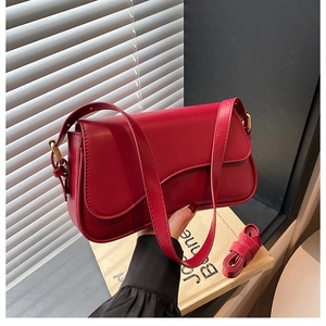 Detail of red leather shoulder bag with matching adjustable strap and vintage flap design