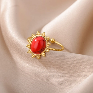Detailed macro of gold ring with oval red stone and sunburst edge on champagne silk