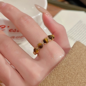 Gros plan de cinq pierres d'oeil de tigre rondes serties sur une bague dorée