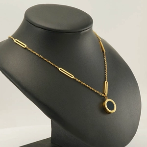 Elegant gold stainless steel necklace with black round pendant on a jewelry display