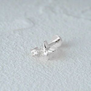 Close-up of a silver star flat back cartilage stud with two sparkling clear gemstones