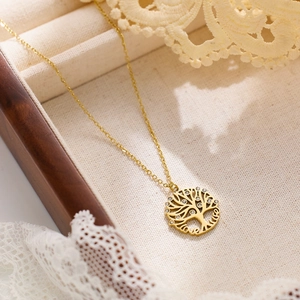 Detailed view of a golden tree of life necklace with Love lettering in a wooden gift box