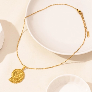 Detailed close-up of a golden nautilus shell pendant necklace on a ceramic decorative plate
