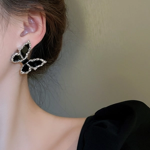 Detailed view of a black butterfly earring with silver metallic edges on model