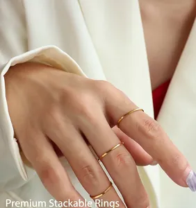 Close-up of minimalist polished gold titanium rings worn on fingers for a layered look