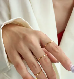 Close-up of minimalist polished gold titanium rings worn on fingers for a layered look