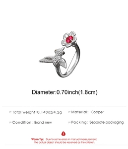 Detailed close-up of hummingbird and flower copper ring with a red gemstone center