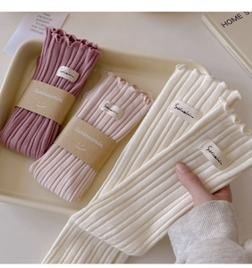 Close-up of ribbed knit socks with lettuce edge trim in pink and off-white colors