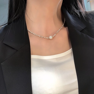 Detailed shot of irregular gold chain with a lustrous white pearl on a model's neck
