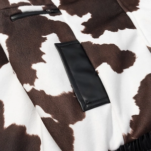 Detail of cow print faux fur jacket with black leather patch and zippered pocket texture