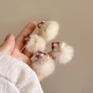Close-up of plush cream hair clips with red and white checkered bows in a set of four