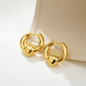 Detailed view of 18K gold two-tone heart hoop earrings on a textured stone base