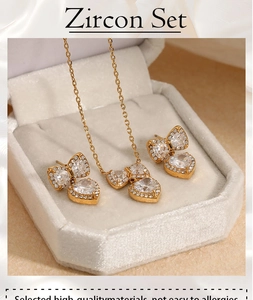 Close-up of golden zircon necklace and earrings set with heart bow motifs in a jewelry box