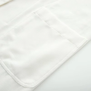Detailed macro view of a white waffle weave fabric pocket on a loose-fit coat