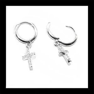 Macro shot of silver hoop earrings with iced out cross pendants and clear crystals