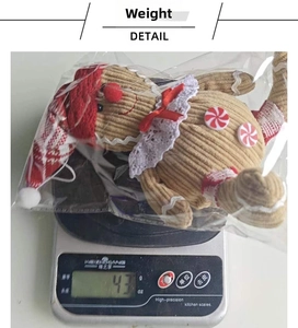 Detail shot of a gingerbread man plush pendant on a scale weighing approximately 43 grams