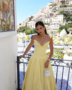 Detail of elegant yellow strapless long dress with fitted waist in a sunny outdoor setting