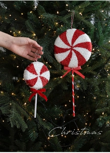 Detail of red and white candy cane ornaments with glitter on a lit Christmas tree