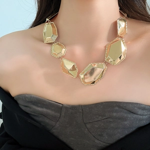 Gros plan d'un collier géométrique doré sur un mannequin montrant des facettes polies