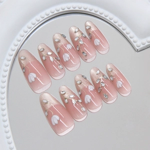 Cat eye press-on nails with floral designs and rhinestones on a pearl tray display