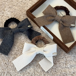 Detailed shot of knitted bow scrunchies in grey, brown and beige with metal charms
