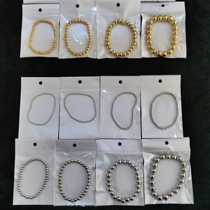 Multiple steel bead bracelets in gold and silver colors organized in sealed plastic bags