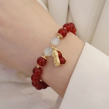 Detailed view of red agate beaded bracelet with white opalite and golden peanut charm