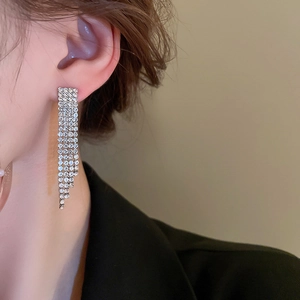Dettaglio di orecchini lunghi a nappa in argento con strass scintillanti indossati