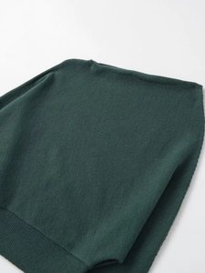 Detail shot of the dark green knit sweater featuring a wide ribbed hem and fine texture