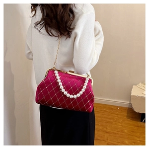 Detail view of red velvet quilted handbag with pearl chain and rhinestone accents
