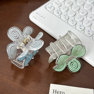 Sweet macaron floral hair claws in blue and green spiral designs on wooden desk